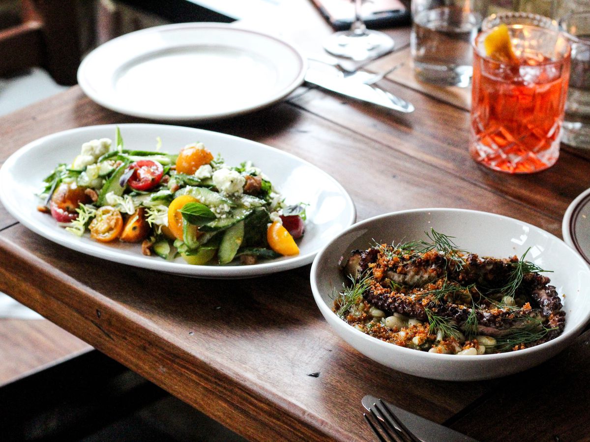 A table set with salad, grilled octopus, and a Negroni cocktail at the Red Hen restaurant in Washington DC.