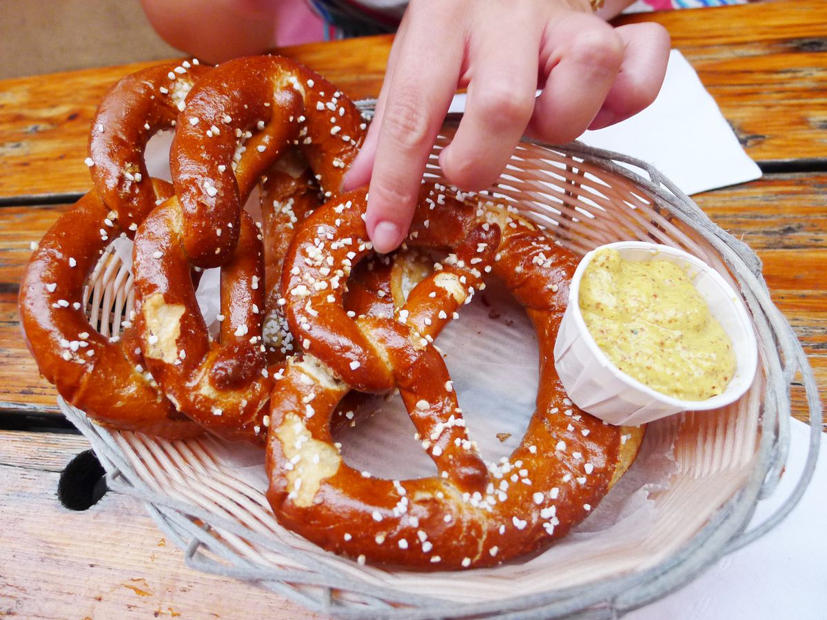 A hand reaches down to pinch one of two salt-studded pretzels.