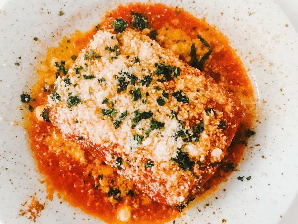 An eggplant parmesan dish is served on a white plate.