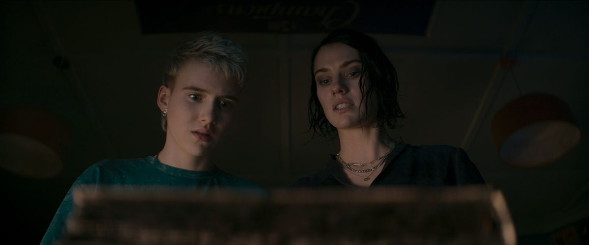 Teenage DJ Danny (Morgan Davies) and his aunt Beth (Lily Sullivan) stare in horror at the Book of the Dead in Evil Dead Rise