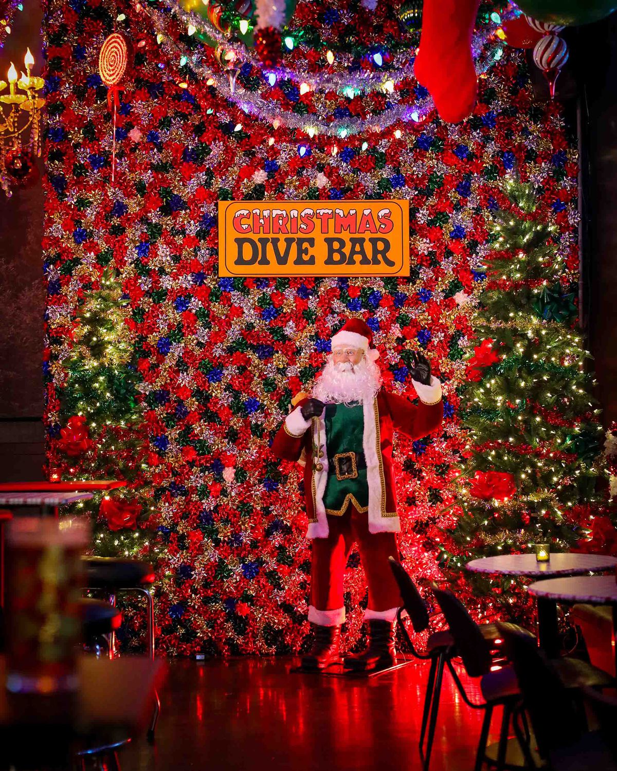 A statue of a Santa beneath a sign that says, “Christmas Dive Bar.”