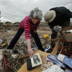 Lea Bessinger salvages a picture of Jesus as she and her son Josh Bessinger sort through the rubble of the elder Bessinger's tornado-ravaged home Tuesday, May 21, 2013, in Moore, Okla. A huge tornado roared through the Oklahoma City suburb Monday, flattening an entire neighborhoods and destroying an elementary school with a direct blow as children and teachers huddled against winds. (AP Photo/Charlie Riedel)