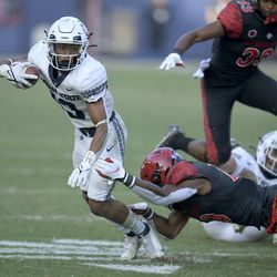 San Diego State safety Trenton Thompson (18) tackles Utah State wide receiver Deven Thompkins (13) in the second half during an NCAA college football game for the Mountain West Conference Championship, Saturday, Dec. 4, 2021, in Carson, Calif.