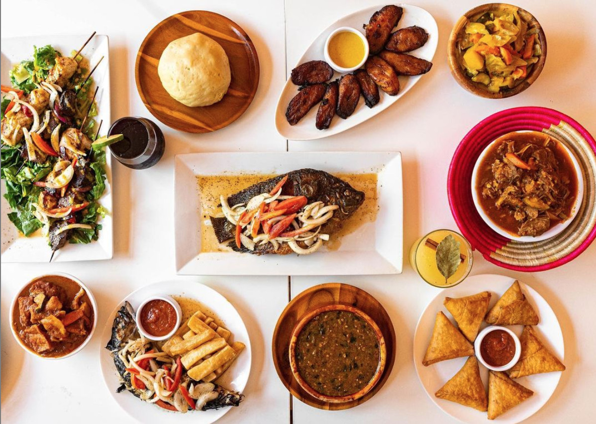 Grilled fish, sweetened plantains, dark stews, and skewers piercing through meat and veggies fill a table.