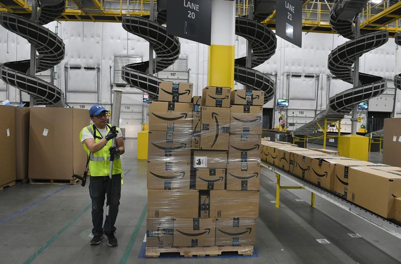An Amazon worker tends to a pallet stacked with boxes inside of a fulfillment center.