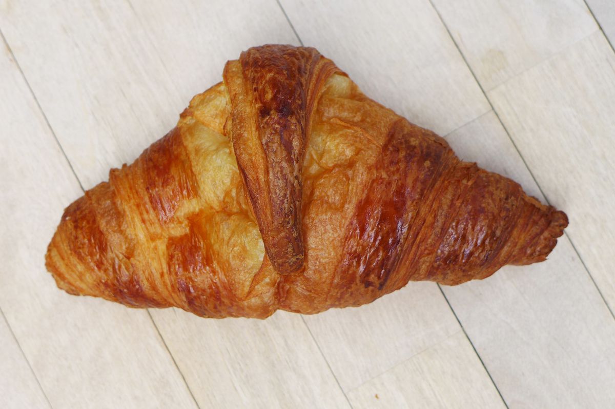 A croissant on a slatted gray background.