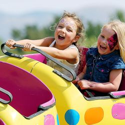 Sabrina Shetler and Kylee Magers laugh as they ride a small roller coaster at the Salt Lake County Fair in South Jordan on Friday, Aug. 4, 2017.