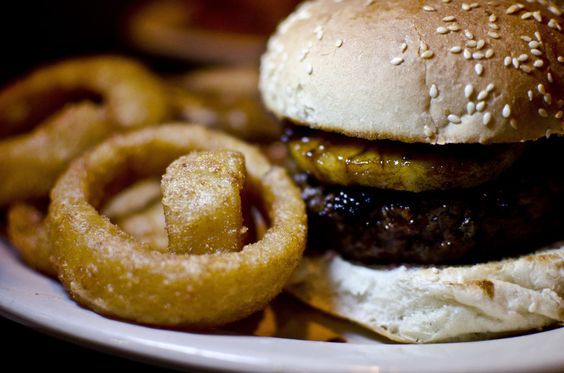Burger topped with pineapple, plus a side of onion rings