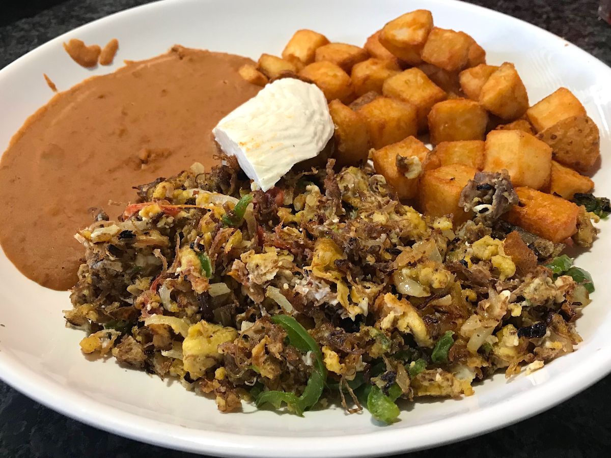 Eggs scrambled with beef on a plate with refried beans and fried potatoes