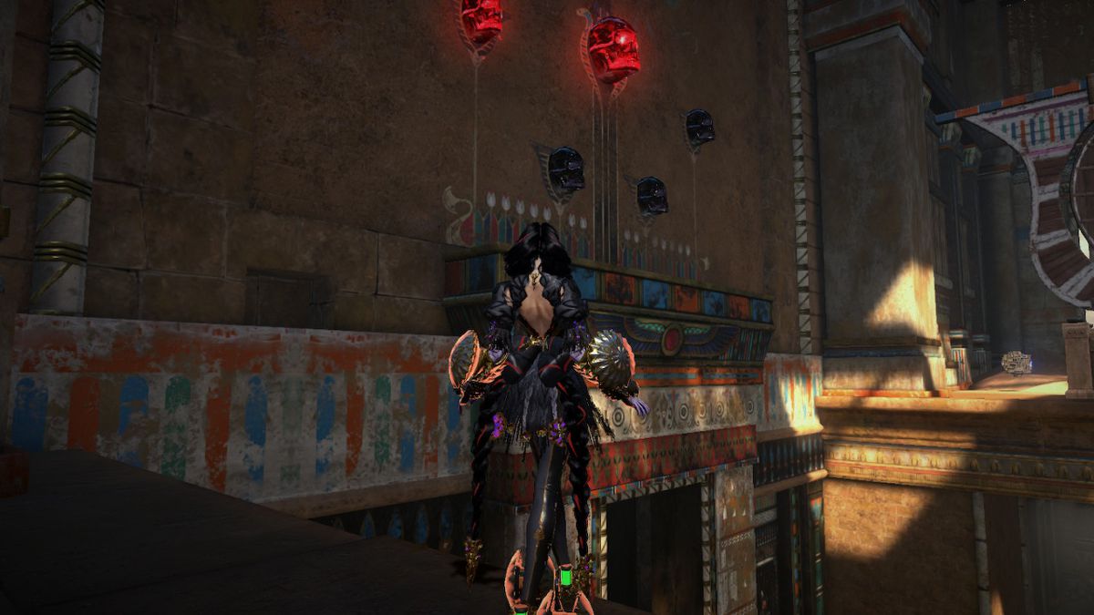 Bayonetta stands on a ledge in the temple, with glowing red skulls in front of her