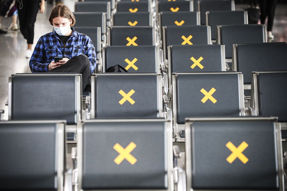 A person sitting alone in a row of seats, many of which are marked with an X.