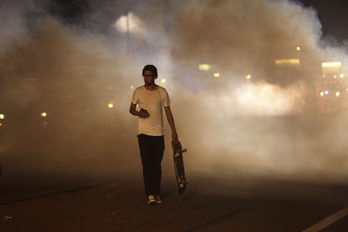 A man with a skateboard walks away from tear gas fired off in Ferguson, Missour, during protests over the police shooting of Michael Brown.