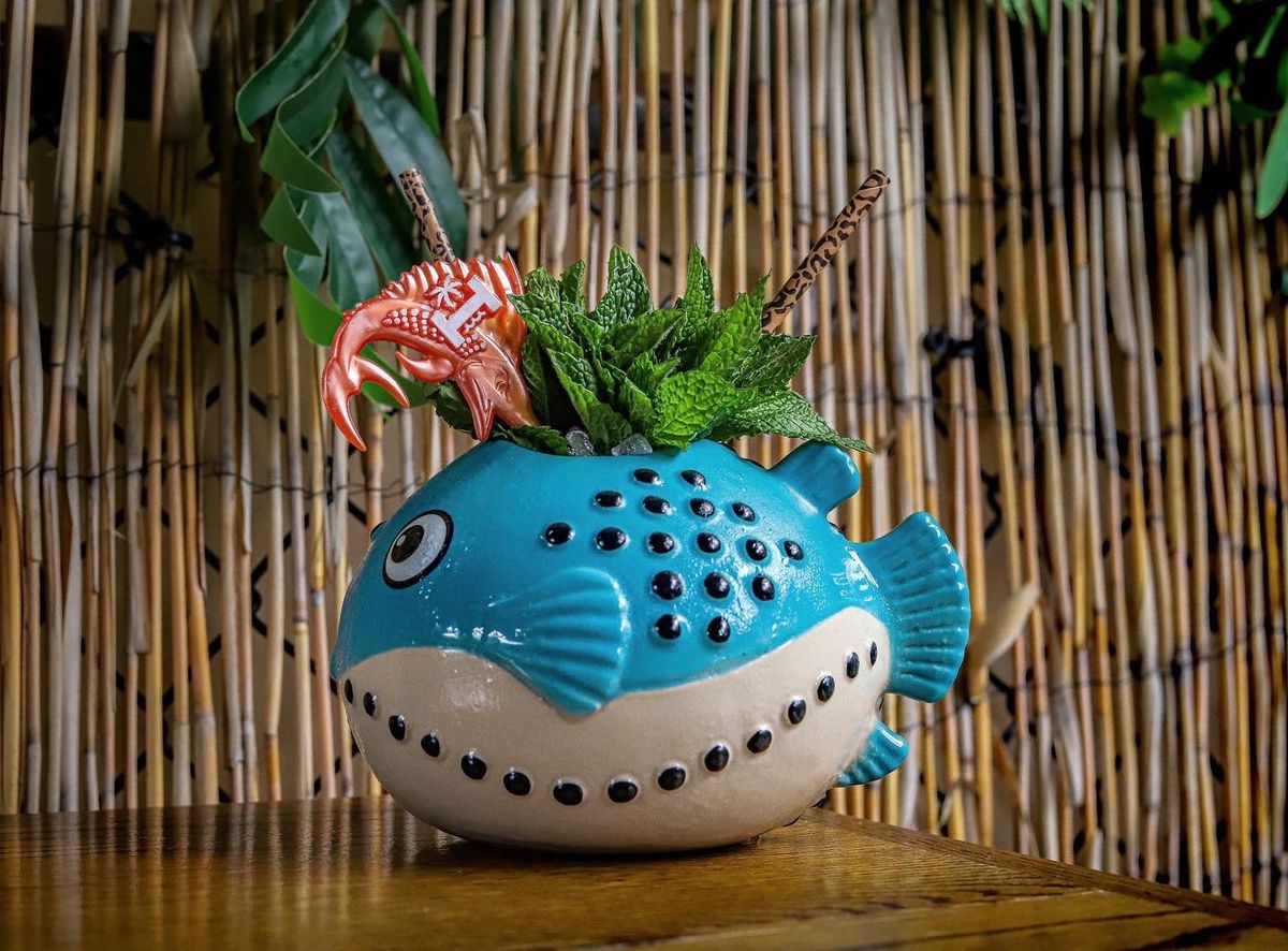 A fish-shaped tiki mug topped with mint and garnishes.