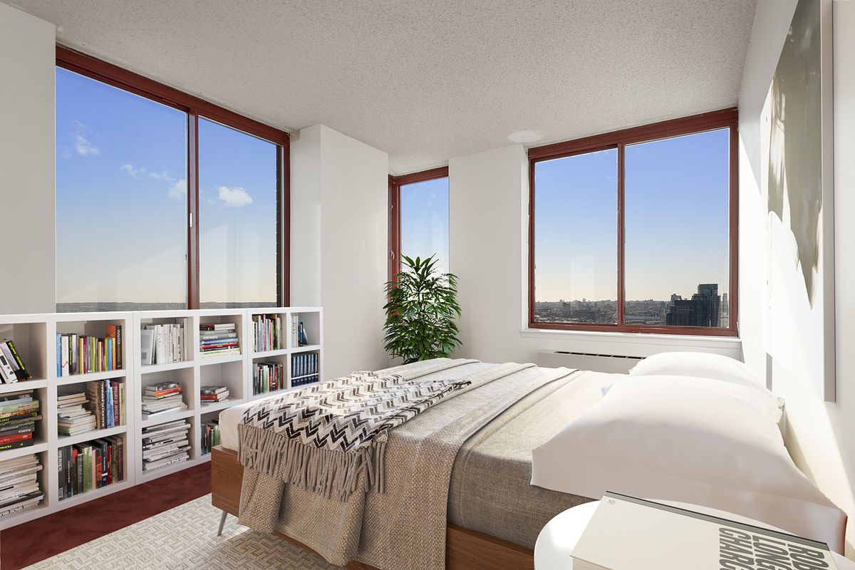 A bedroom with a medium-sized bed, large windows, several bookshelves, and white walls.