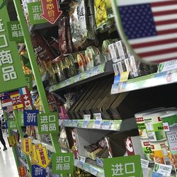 Women push a shopping cart near nuts and sweets imported from the United States and other countries displayed on a section selling imported foods at a supermarket in Beijing, Monday, April 2, 2018. China raised import duties on a $3 billion list of U.S. pork, fruit and other products Monday in an escalating tariff dispute with President Donald Trump that companies worry might depress global commerce. (AP Photo/Andy Wong)
