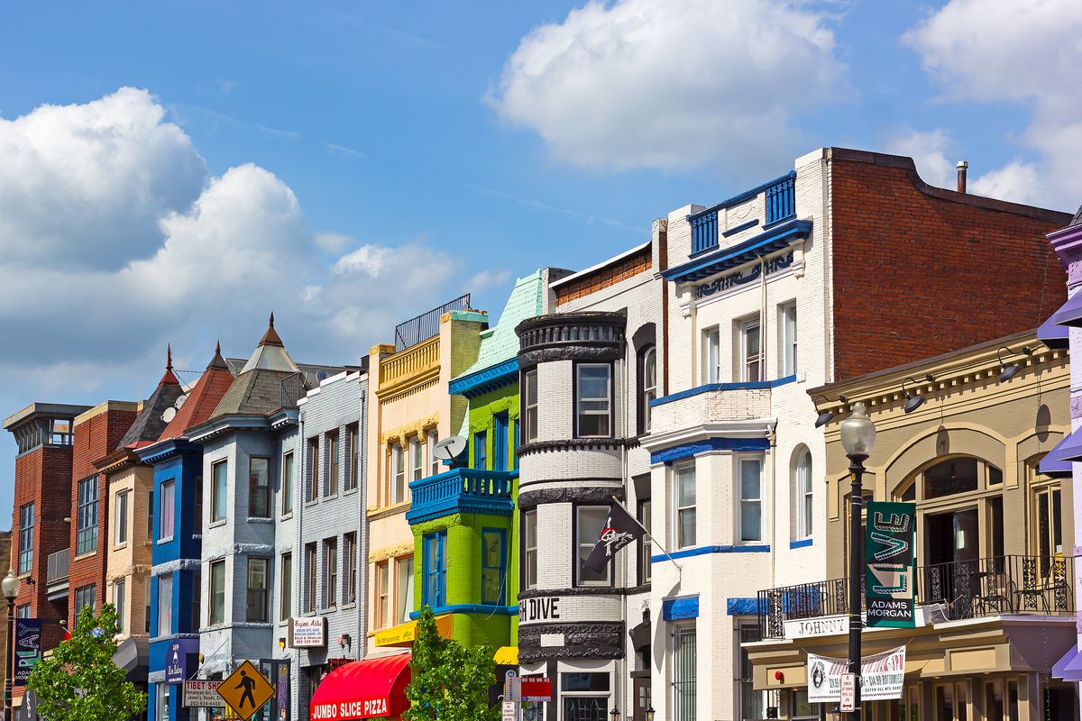 A row of buildings housing businesses on 18th Street NW in Adams Morgan. The buildings are of various colors but most are three stories.