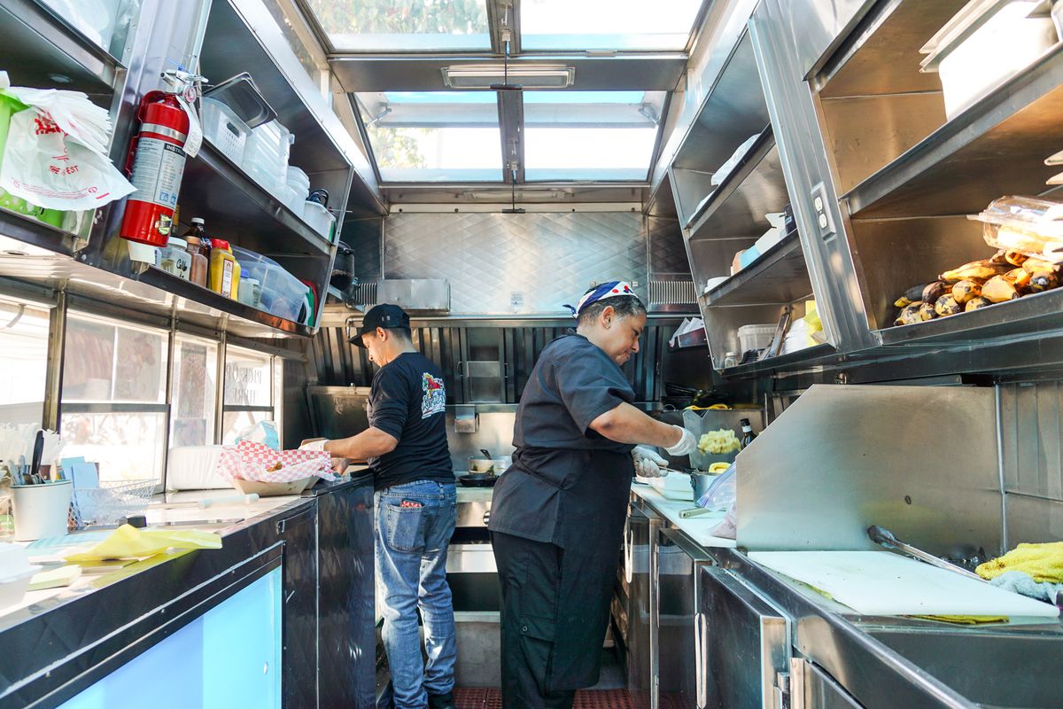 A male and female cook prepare dishes inside of a food truck in Los Angeles.