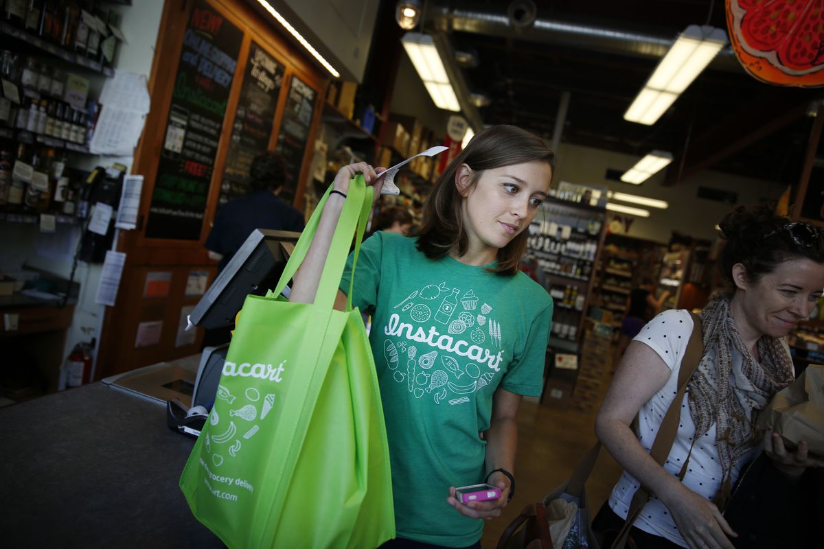 Instacart personal shopper, Sydney Hollingsworth, carries a customer’s order after purchasing it at the Bi-Rite Market on Divisadero Street on Thursday, July 24, 2014 in San Francisco, Calif.