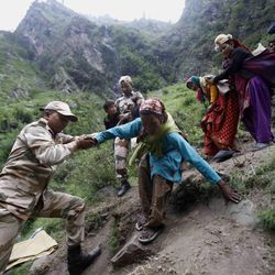 Indian army soldiers help stranded people climb down a mountain in Govindghat, India, Sunday, June 23, 2013. Bad weather hampered efforts Sunday to evacuate thousands of people stranded in the northern India state of Uttarakhand, where at least 1,000 people have died in monsoon flooding and landslides, army officials said. 
