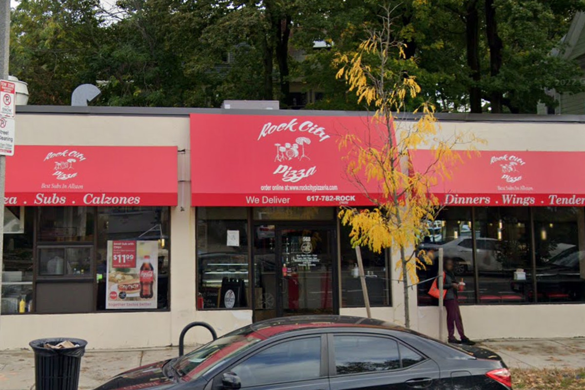 An exterior photo of a restaurant with red canvas awnings and white lettering spelling out “Rock City Pizza.”
