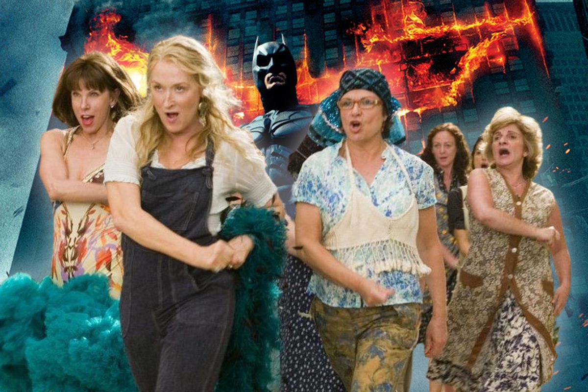 The Mamma Mia ladies marching forward in front of the poster of the Dark Knight featuring Batman and a burning building