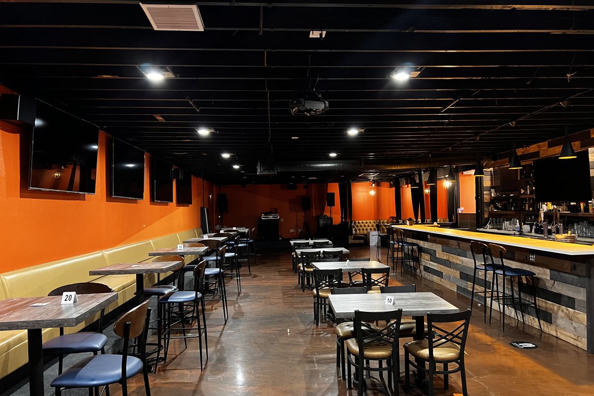 A bar with tables and orange walls.