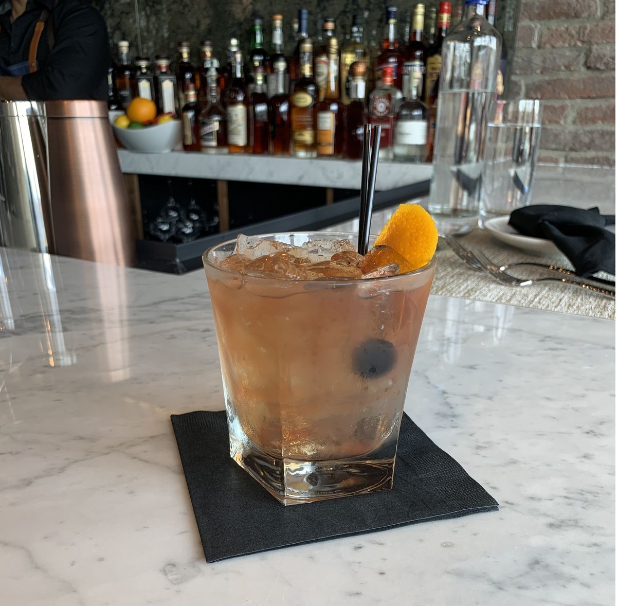 Un cocktail dans un verre à whisky sur un plateau de bar en marbre blanc 