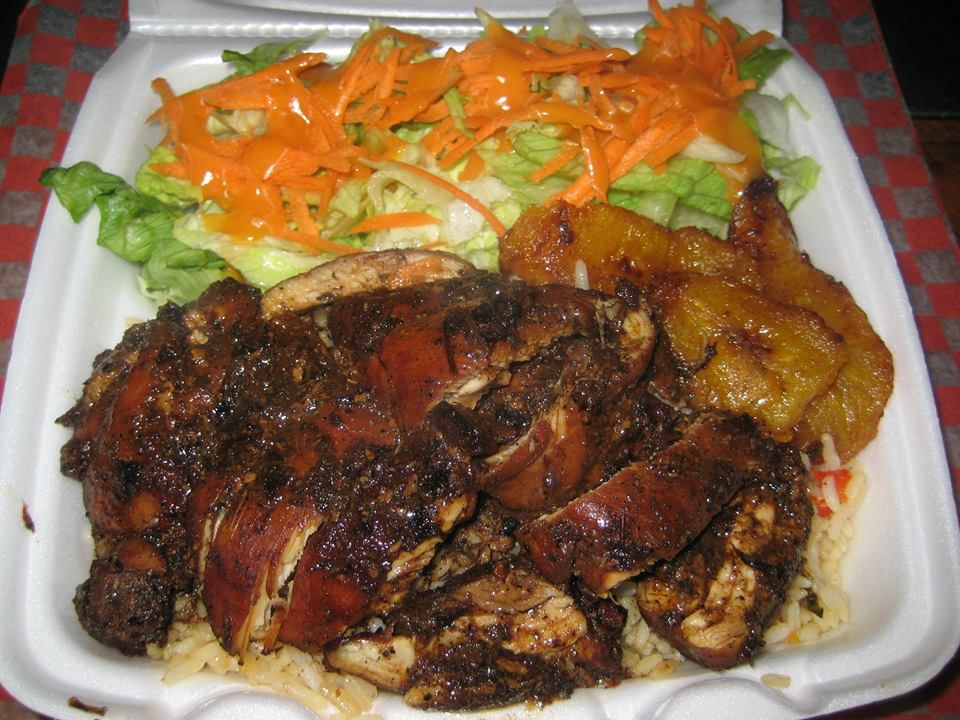 A plate of cut-up meat on top of rice with a carrot-heavy salad in a styrofoam container.