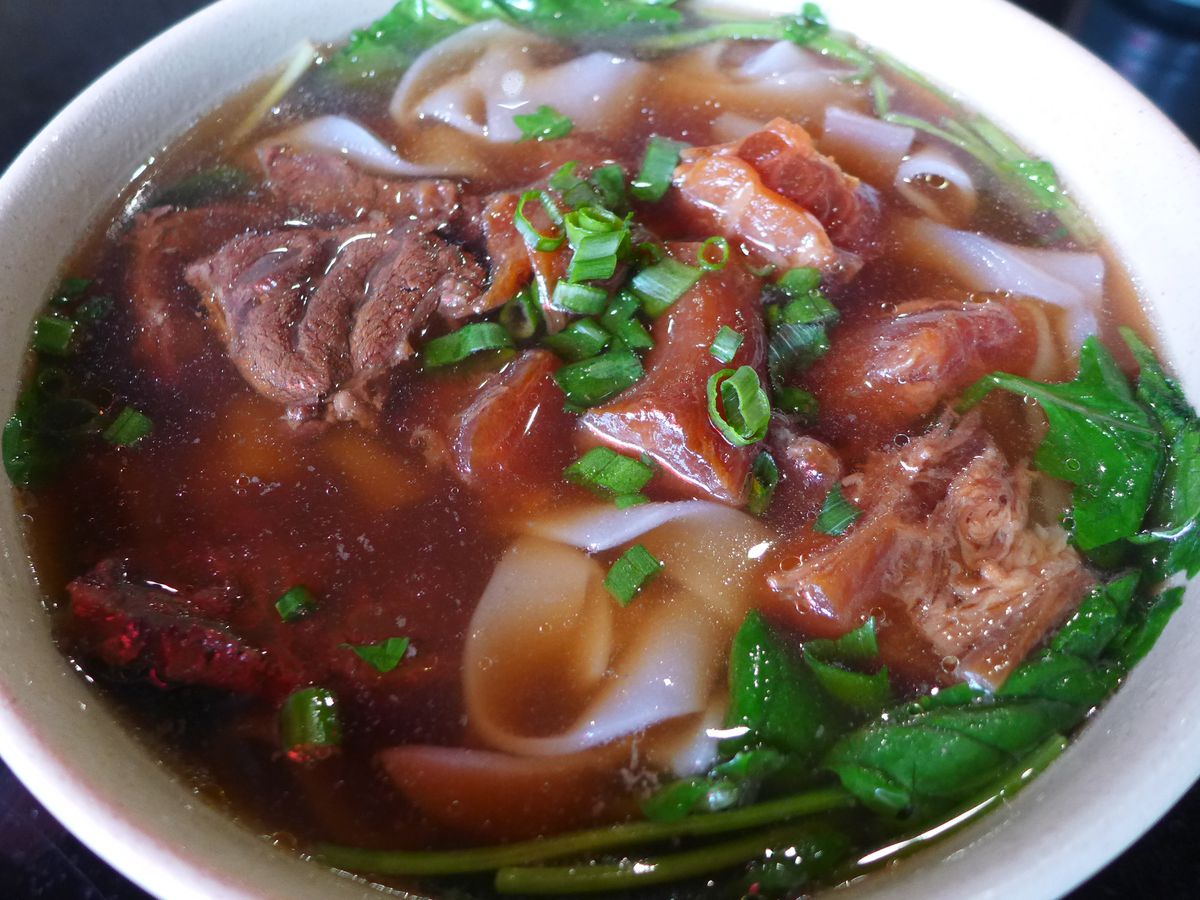 A reddish broth teeming with noodles and chunks of beef.