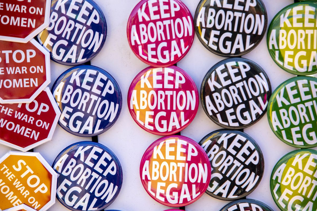 Rows of colorful stickers and buttons say “Keep abortion legal” and “Stop the war on women.”