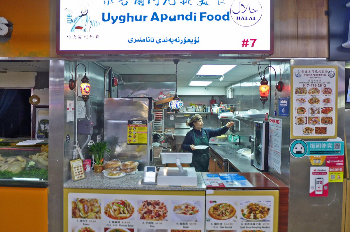 A brightly lit stall in a downstairs supermarket food court, with a woman seen through the window.