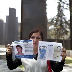 Yolanda Colin shows pictures of her nephew, missing since 2011, as she stands by the new memorial in honor of victims of violence during its unveiling in Mexico City. Friday.  