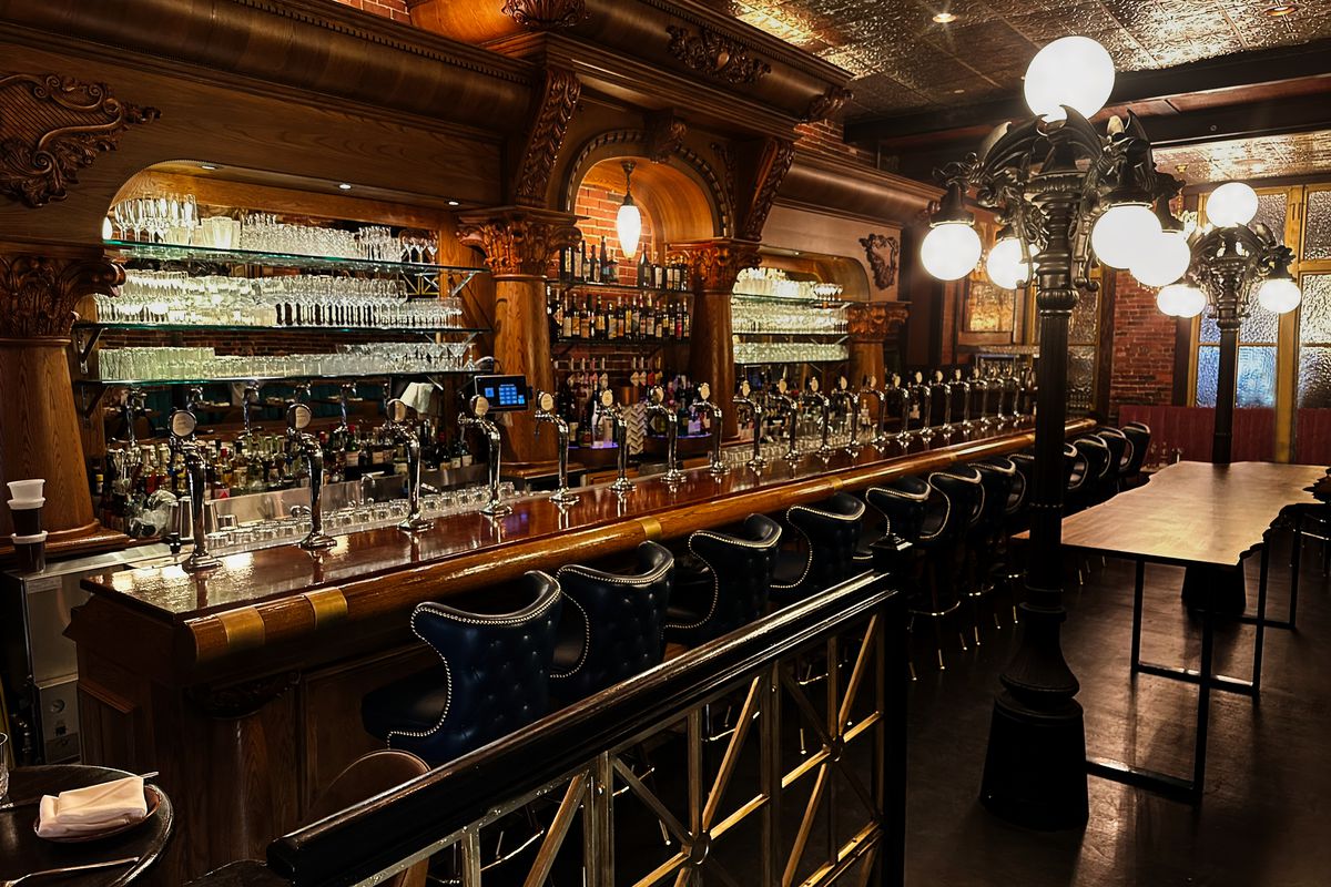 A shiny, dark wooden bar with two lamps decorated with gargoyles in front of the bar.