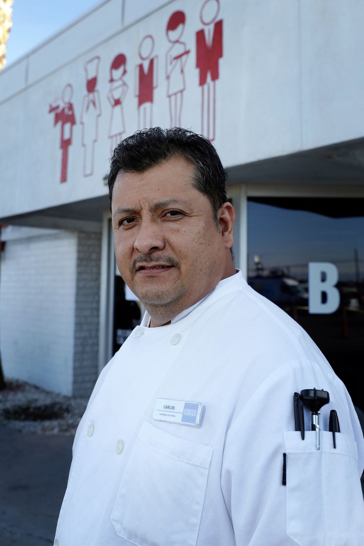 A man in a chef’s coat looks into the camera.