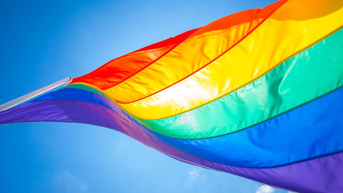 A rainbow pride flag flying against blue skies
