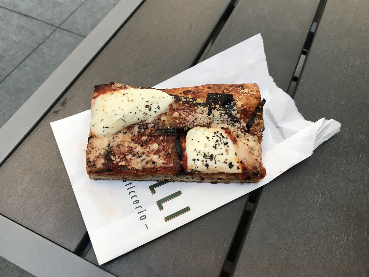 A square slice of eggplant parm focaccia on a table.