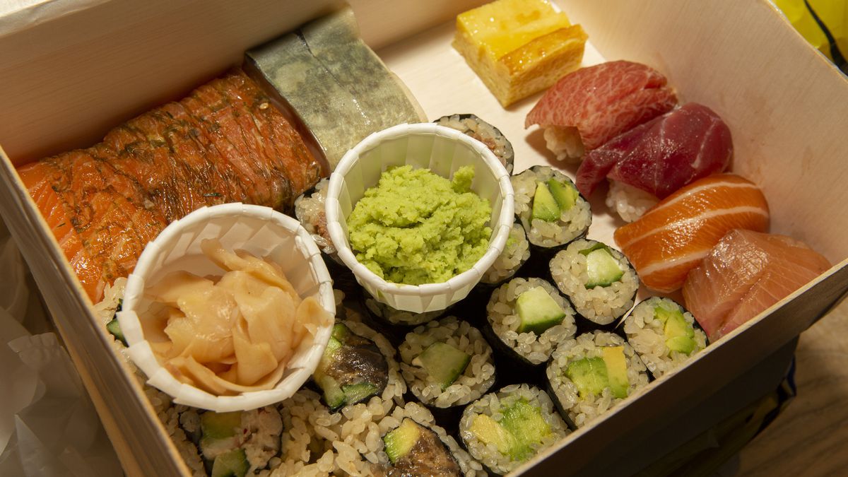 A bento box stuffed with various pieces of sushi with a ramekin of wasabi in the middle.