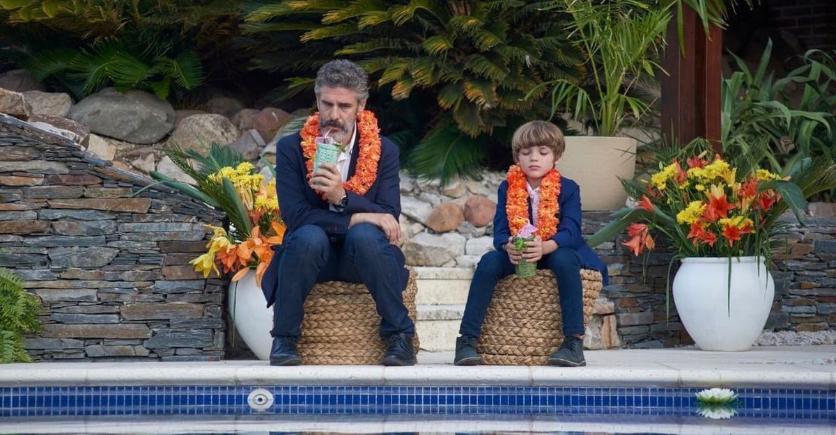 David (Leonardo Sbaraglia) et son fils Benito (Benjamín Otero) assis au bord d'une piscine en train de boire du jus dans Today We Fix The World.