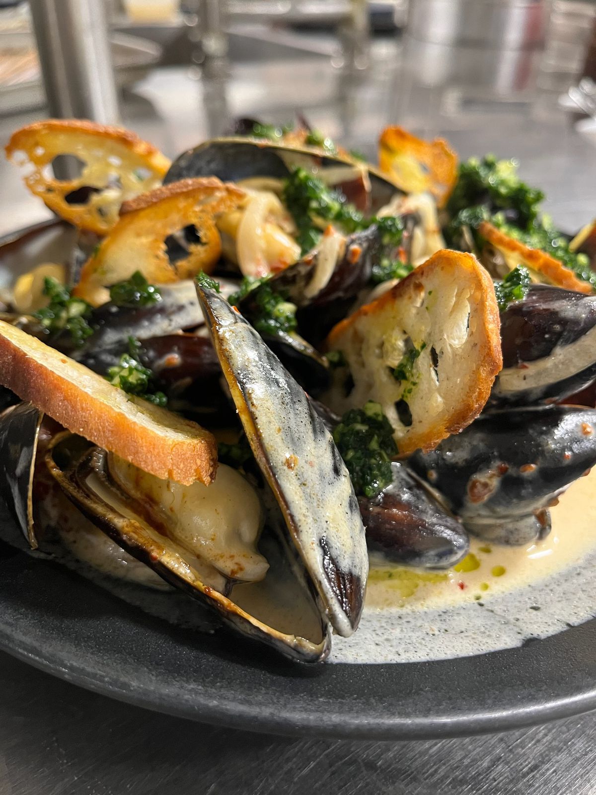 A black bowl filled with cooked mussels.