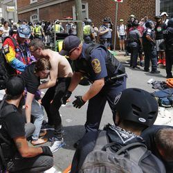 Rescue personnel help injured people after a car ran into a large group of protesters after a white nationalist rally in Charlottesville, Va., Saturday, Aug. 12, 2017. The nationalists were holding the rally to protest plans by the city of Charlottesville to remove a statue of Confederate Gen. Robert E. Lee. There were several hundred protesters marching in a long line when the car drove into a group of them. 