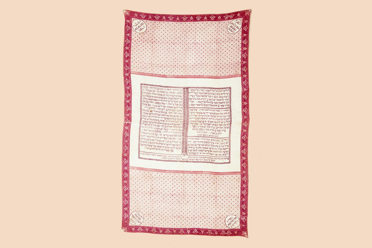 A red and white scarf textile with Hebrew text