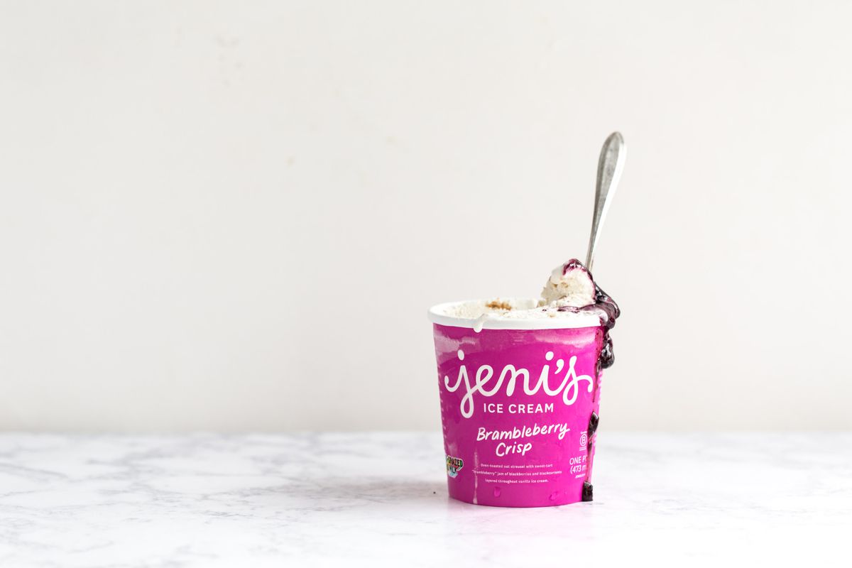 a pink pint of jeni’s brambleberry crisp ice cream with a spoon in the center