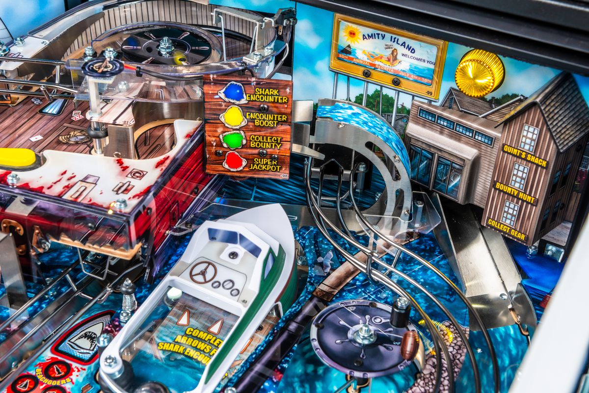 A close up photograph of the playfield of the pinball table Jaws, focused on the wave-scoop ramp that leads to the Orca fishing boat raised playfield