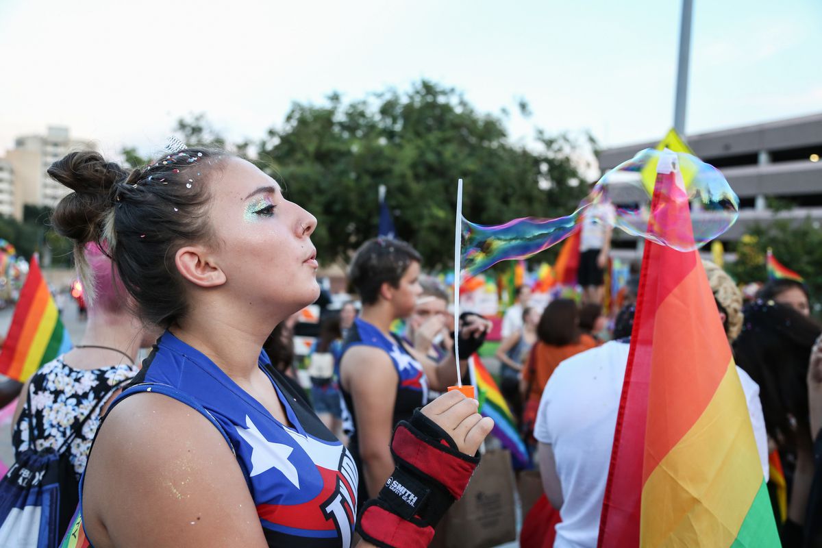Photo of a woman blowing a soap bubble with Pride flag
