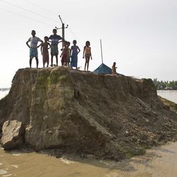 Flood affected villagers wait for relief material on a broken road washed away by floodwaters in Morigaon district, east of Gauhati, northeastern state of Assam, Tuesday, Aug. 15, 2017. Heavy monsoon rains have unleashed landslides and floods that killed dozens of people in recent days and displaced millions more across northern India, southern Nepal and Bangladesh. (AP Photo/Anupam Nath)