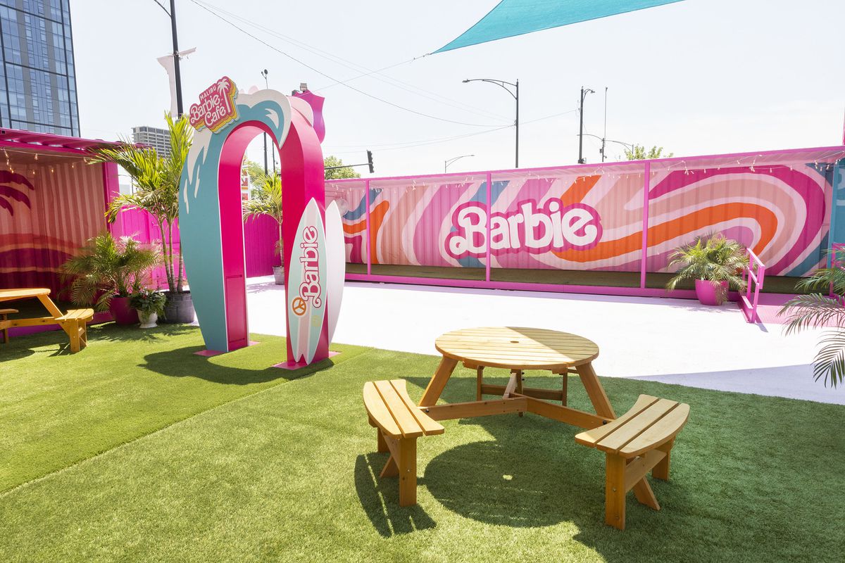 A large outdoor patio decorated with pink Barbie art and logos.