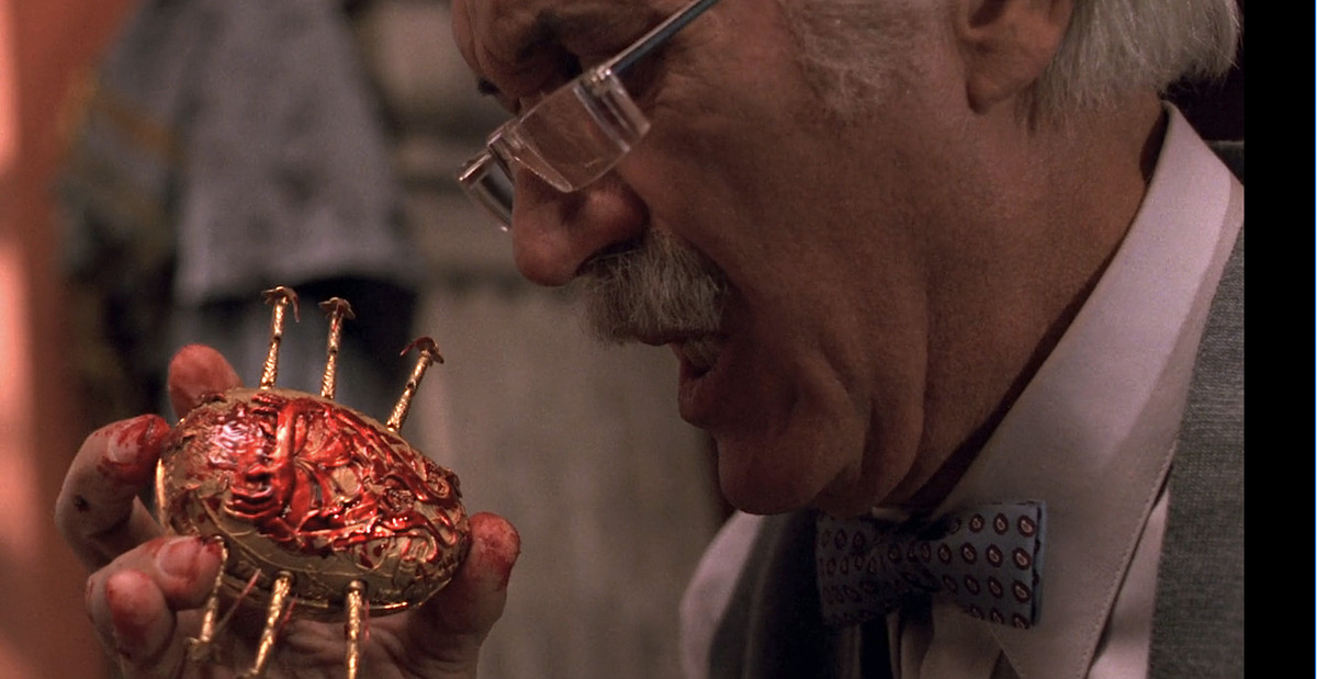 Elderly antiques dealer Jesús Gris (Federico Luppi), a white-haired man with rimless glasses, winces as he holds a golden mechanical scarab covered with his blood in Guillermo del Toro’s Cronos