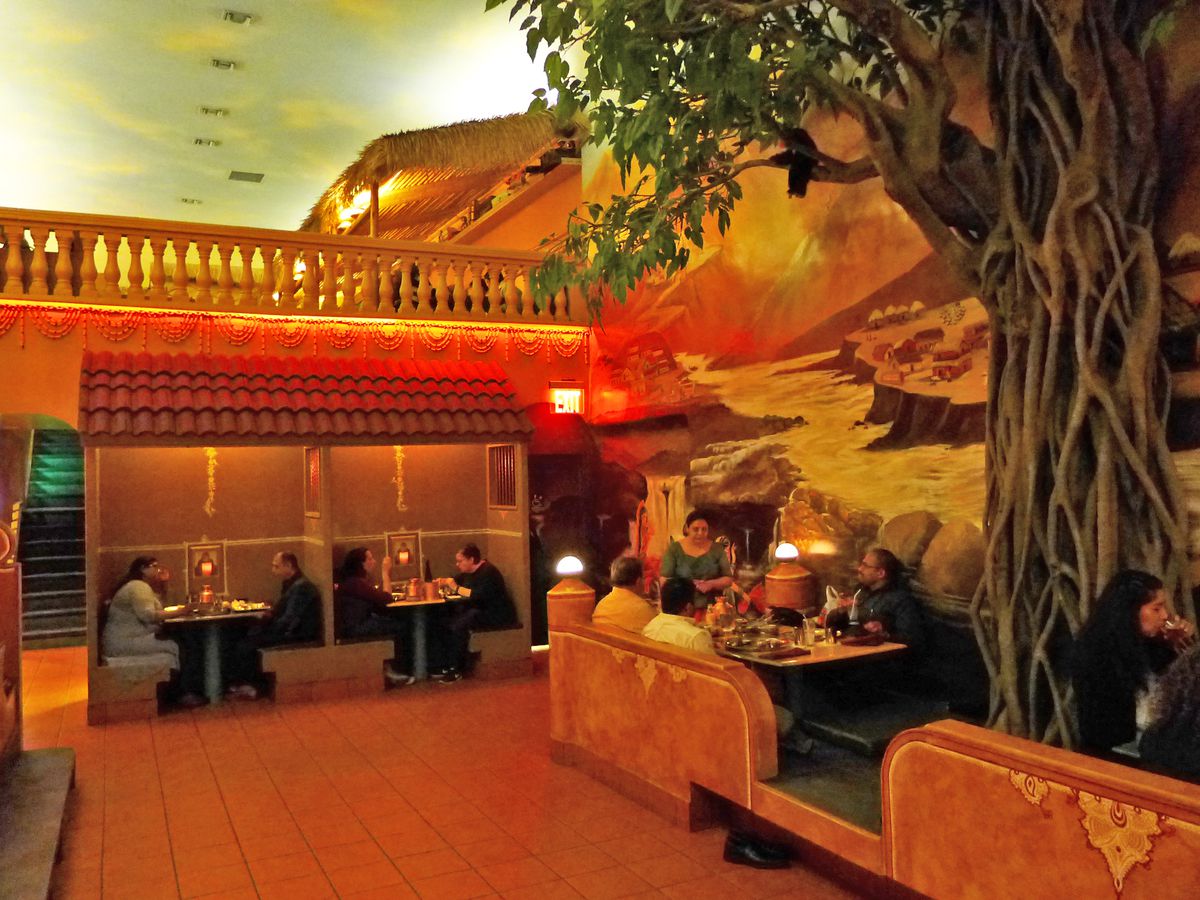 A small structure, a balcony, and a tree are all part of the landscape inside the restaurant.