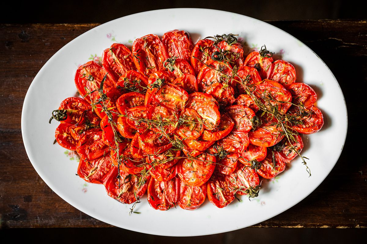 A big platter of roasted tomatoes with fresh thyme sprigs.