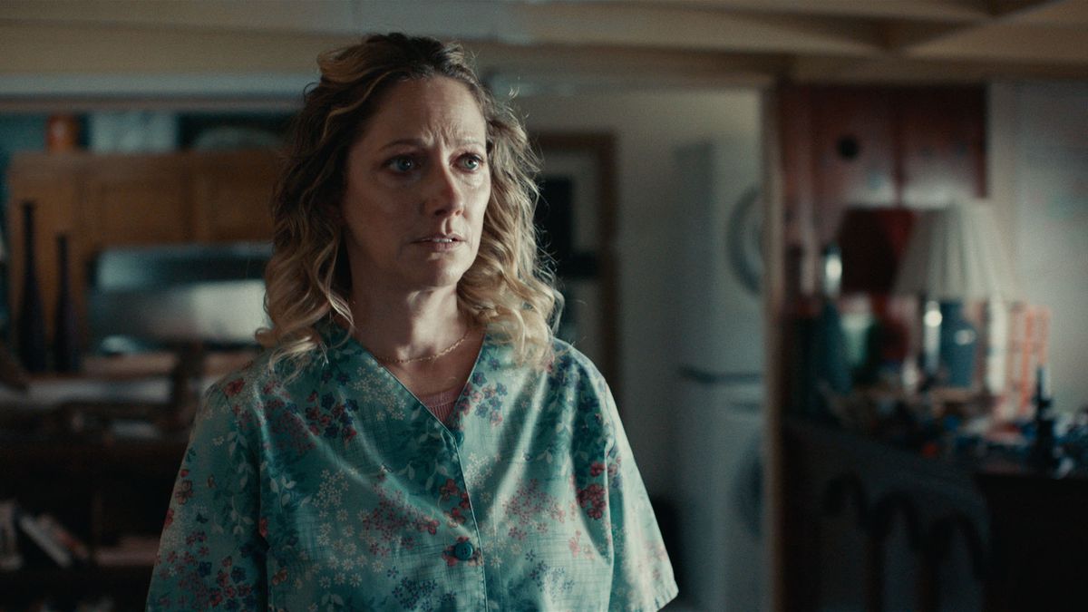 Sophie (Judy Greer), a middle-aged woman in hospital scrubs, stands in front of the nursing station at her hospital and looks unnerved at something offscreen in Aporia